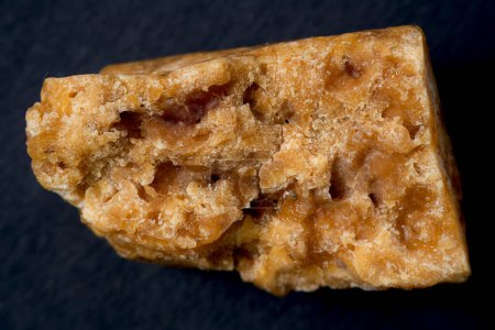 An unevenly shaped Asafoetida, captured in a close-up shot, isolated against a black background.