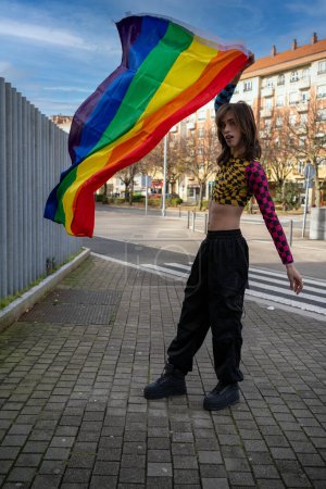 joven vestido con ropa colorida y apretada ondeando la bandera del orgullo en el concepto del día wind.pride