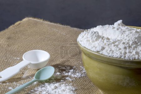 Téléchargez les photos : All-purpose flour in a ceramic bowl with a measuring spoon, all-purpose flour and eggs can be used to make a variety of baked goods and other dishes - en image libre de droit