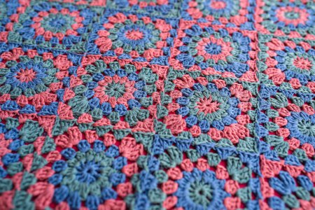 Téléchargez les photos : Granny carrés crochet afghan dans les couleurs rouge, bleu et vert. Texture motif au crochet avec la couleur rouge en dessous. - en image libre de droit