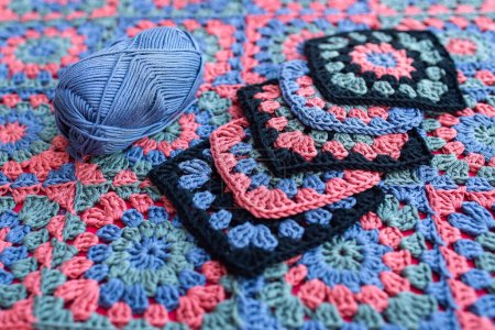 Téléchargez les photos : Granny carrés crochet motifs contrastent couleurs et un écheveau de fil placé sur un afghan. Texture des modèles de crochet. - en image libre de droit