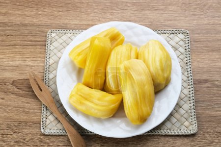 Fresh and ripe jackfruit served on a plate on a wooden table. 