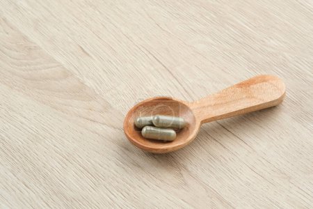 Foto de Medicina herbal en cápsulas en una cuchara de madera - Imagen libre de derechos