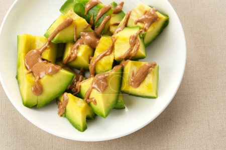 Avocado mit Mandelbutter auf weißem Teller
