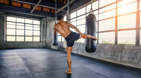 Photo for Muay thai fighter training in gym with punching bag - Royalty Free Image