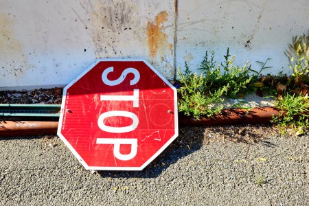 Foto de Stop Sign Laying on the Street Next to Barrier, Center of Frame - Imagen libre de derechos
