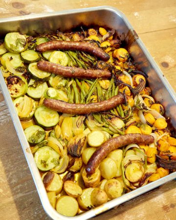 Foto de Variedad de verduras asadas y salchichas en una sartén - Imagen libre de derechos