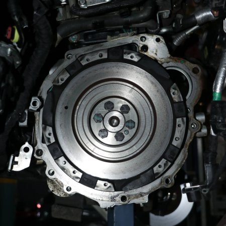 metallic flywheel mount on the transmission assembly of a vehicle in a auto repair shop in closeup