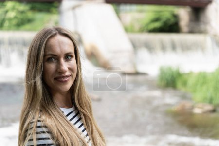 Photo for Focus on foreground on a smiling long-haired woman against the background of the river. - Royalty Free Image