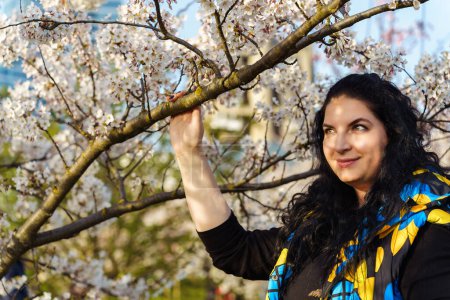 Young woman on the background of blooming cherry trees in the city.