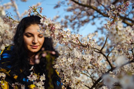 Attractive young woman enjoying spring among flowering trees in cherry orchard.