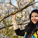 Attractive young ukrainian woman smiling in blooming cherry orchard in spring.