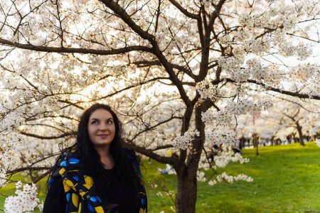 Beautiful plus-size woman in a blooming cherry garden in spring time.