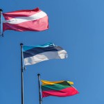 The flags of the three Baltic countries, Lithuania, Latvia and Estonia flutter against a clear blue sky.