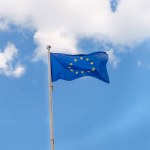 EU flag waving on blue sky background with clouds.