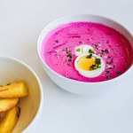 A plate with traditional Lithuanian cold summer soup of beetroot and kefir Saltibarsciai or Lithuanian kholodnik or cold borscht with baked potato wedges.