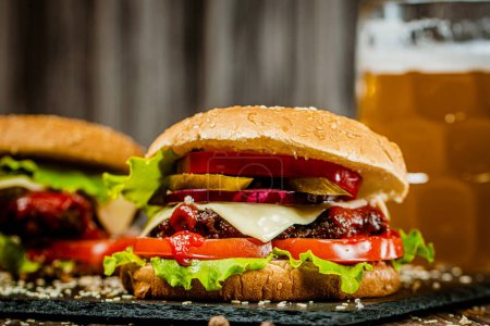 Nahaufnahme frischen Appetit hausgemachte Rindfleisch-Burger auf einem Holztisch mit einem Glas Bier. Selektiver Fokus. Junk food 