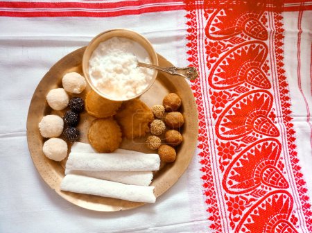 Téléchargez les photos : Produits alimentaires traditionnels assamais comme la pitha, laddu, doi sira avec fond gamosa assamais avec motifs japi - en image libre de droit