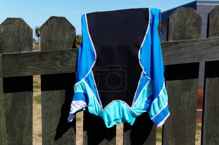 Photo for A rash shirt is worn for extra warmth or protection against the sun, or stingers. It has been hung over a fence to dry after use. - Royalty Free Image