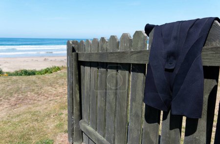 Photo for A shorty wetsuit is hanging on a fence to dry, its been having fun in the sea nearby. - Royalty Free Image
