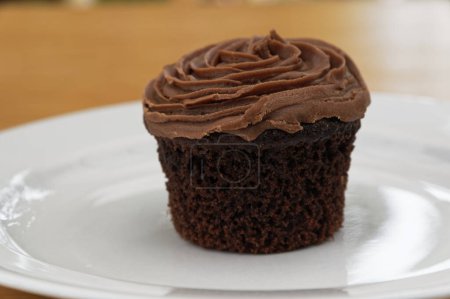 Photo for A freshly baked chocolate cupcake has had its baking liner removed and is ready to be enjoyed. - Royalty Free Image