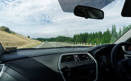 Ein Blick durch die Windschutzscheibe eines rechtsgelenkten Fahrzeugs. Das Auto fährt auf einer Autobahn in Neuseeland.
