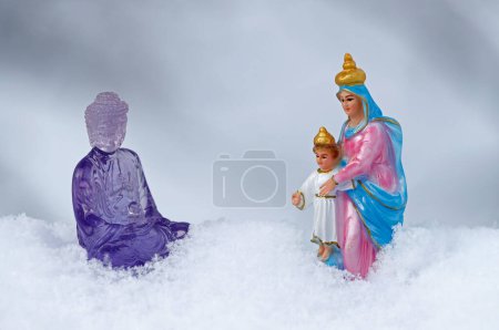 Foto de Purple plastic buddha  and Virgin Mary statues in the snow.  France. - Imagen libre de derechos