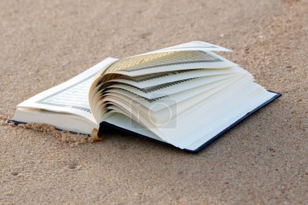 Téléchargez les photos : Open Quran on sand beach.  Symbol of Islam. - en image libre de droit