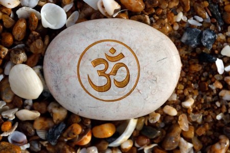 Téléchargez les photos : Stone on a beach with the Om or Aum symbol of Hinduism and Buddhism. - en image libre de droit