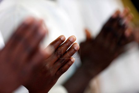 Iglesia africana. Misa católica dominical. Hombre rezando. Primer plano en las manos. Agbonou Koeroma. Togo.. 