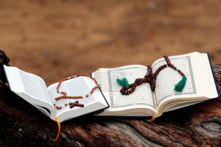 Téléchargez les photos : Prayer beads, open Kuran and open Holy Bible on a trunk. Interfaith symbols. - en image libre de droit