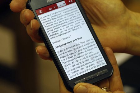 Téléchargez les photos : Église évangélique protestante. Femme lisant la Bible sur un smartphone. Cluses. France. - en image libre de droit