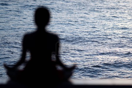 Téléchargez les photos : Silhouette de femme méditant en position de yoga lotus en face de la mer. Tiens bon. Cambodge. - en image libre de droit