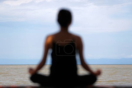 Téléchargez les photos : Silhouette de femme méditant en position de yoga lotus en face de la mer. Tiens bon. Cambodge. - en image libre de droit