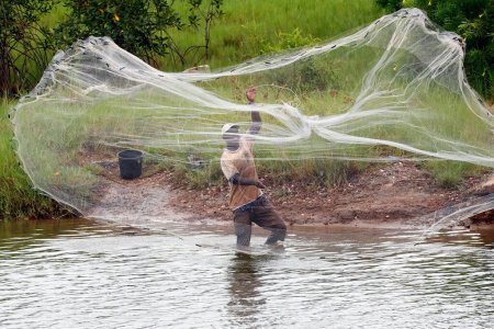 Téléchargez les photos : Pêcheur africain jetant un filet dans la rive - en image libre de droit