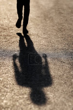 Téléchargez les photos : Woman  walking and projecting long shadow on the street.  Hanoi. Vietnam. - en image libre de droit