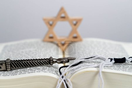 Foto de Un puntero ritual judío Yad plateado, una estrella judía o estrella de David y una Torá. Símbolos judíos. Símbolo religioso. - Imagen libre de derechos