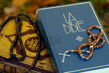 Photo for Holy Quran in french  with a muslim prayer beads and bible with rosary.  Interfaith symbols between Christianity and Islam France. - Royalty Free Image