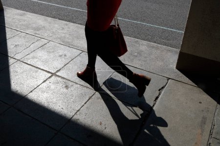 Téléchargez les photos : Silhouette et ombre de femme marchant dans la rue. Gros plan. - en image libre de droit