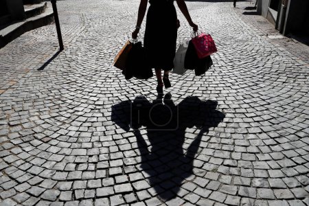 Téléchargez les photos : Femme avec sacs à provisions en silhouette avec ombre. - en image libre de droit
