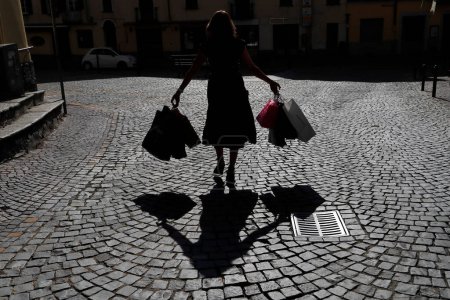 Téléchargez les photos : Femme avec sacs à provisions en silhouette avec ombre. - en image libre de droit