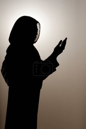 Téléchargez les photos : Silhouette de femme musulmane en abaya prie les mains en l'air. Concept de prière religieuse. Émirats arabes unis - en image libre de droit