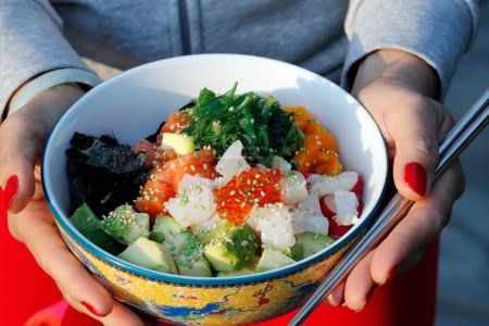 Téléchargez les photos : Cuisine asiatique. Poke bowl aux algues, avocat, concombre, radis, graines de sésame. - en image libre de droit