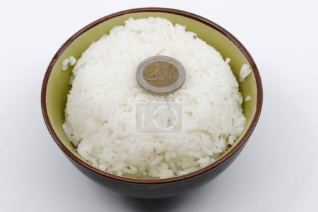 Foto de Concepto de dinero y comida. Moneda en un tazón de arroz blanco al vapor. - Imagen libre de derechos