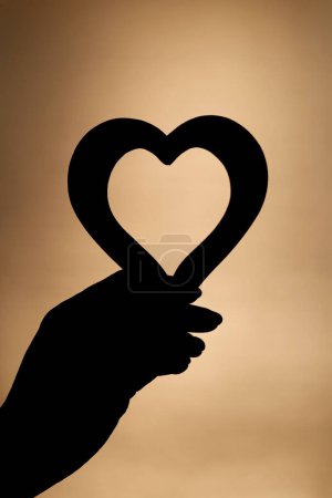 Téléchargez les photos : Femme tenant un cœur en bois au coucher du soleil. Amour ou Saint-Valentin concept. - en image libre de droit