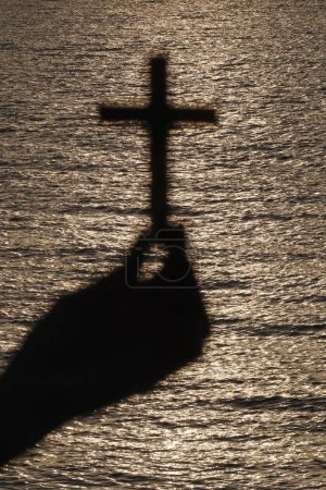 Téléchargez les photos : Femme fidèle priant avec la croix chrétienne au coucher du soleil. Gros plan sur la main. Concept de religion, foi, prière et spiritualité. - en image libre de droit