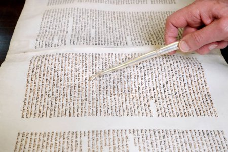 Photo for Rabbin holding a yad, reading an ancient Torah scroll.  Yom Kippur. - Royalty Free Image