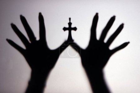 Photo for Silhouette of hands showing a catholic cross on white background.  Symbol of christianity and faith. - Royalty Free Image