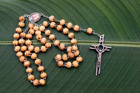 Rosary or prayer beads on a green leaf. Jesus on the croos. Crucifix.