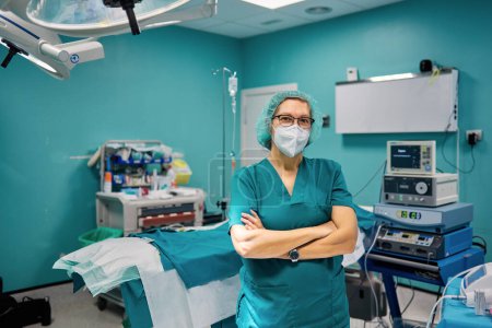 Photo for Self assured female doctor in medical uniform looking at camera with folded arms in hospital - Royalty Free Image